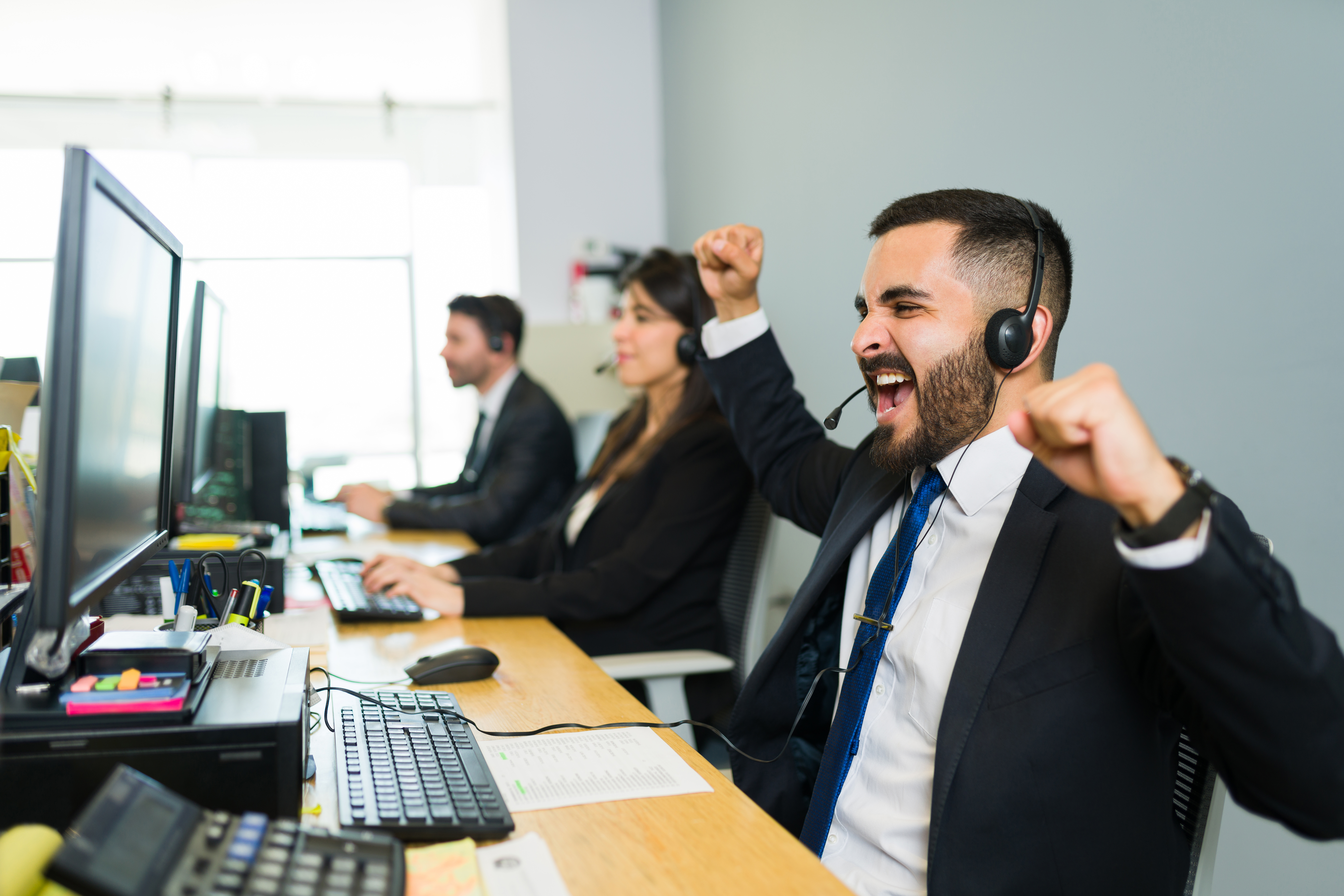 Celebrating a huge sales deal. Handsome man in his 30s shouting with happiness after winning a business deal with a customer at a call center